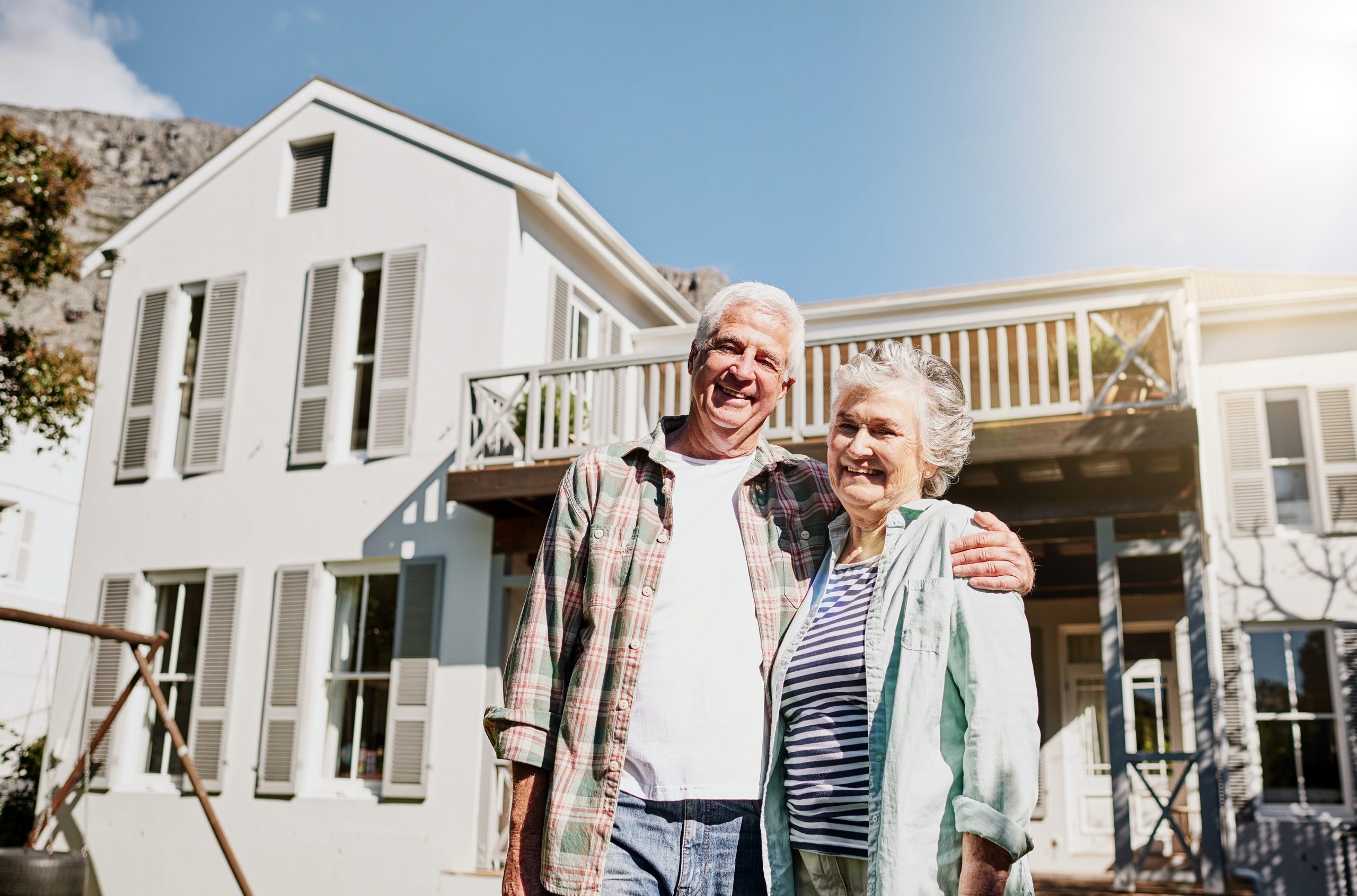 Shot of a happy senior couple after a reverse mortgage standing together in front of their house.